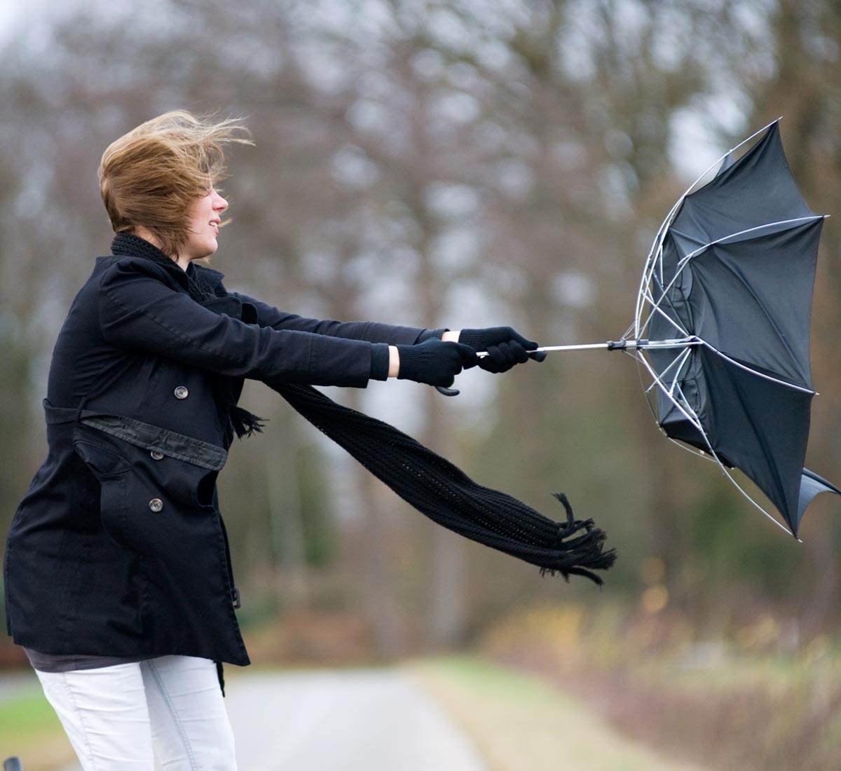 Young woman struggling with an umbrella on a windy Autumn day