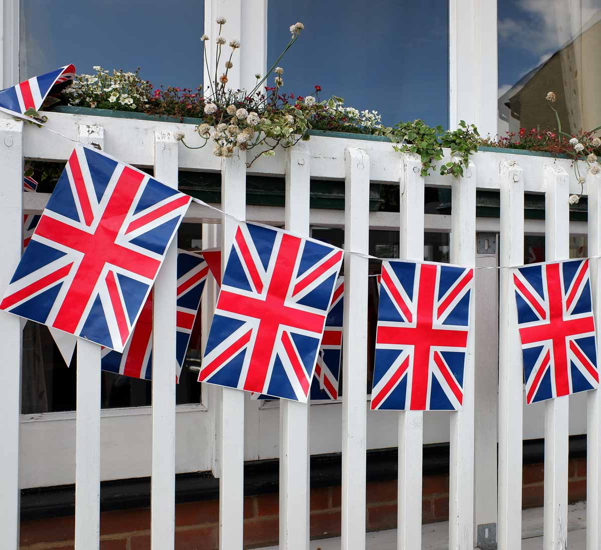Union flag bunting hanging on white fence celebrating VE Day