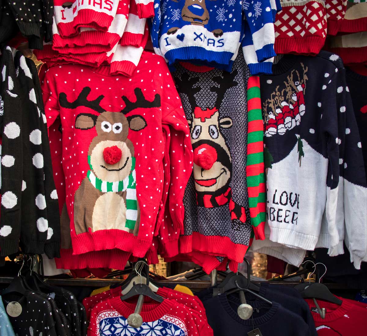 Selection of tacky Christmas jumpers displayed in a market