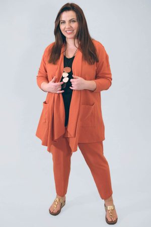 The model in this photo is wearing a Noen two piece cotton suit of waterfall jacket and crop trousers in rust from Bakou in West Wimbledon